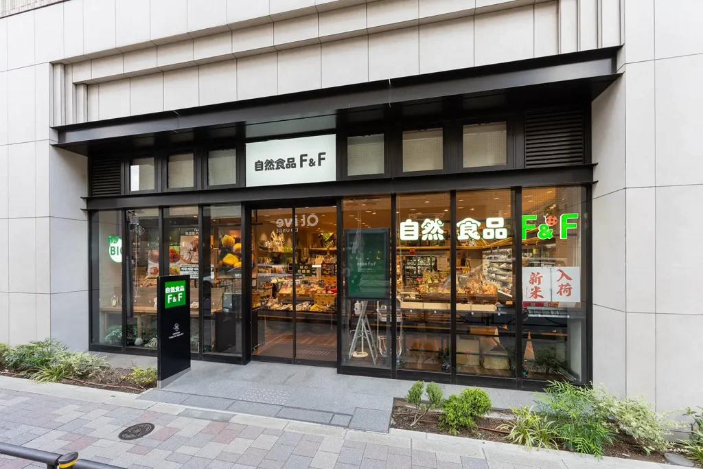 自然食品F&F都立大学店 店舗入り口外観 ガラス張りのドアに、白と緑をベースにした店舗ロゴがかかれている